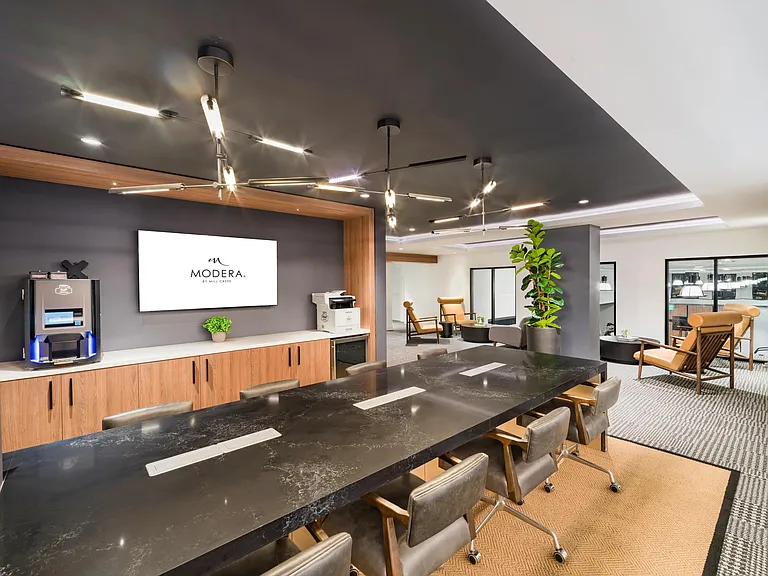 A design-forward conference space at Modera Aventura, featuring integrated technology, warm wood accents, and flexible seating for focused work or collaboration.