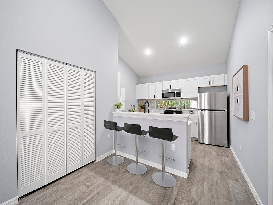 Kitchen with appliances, white cabinets, bar counter and bar height stools