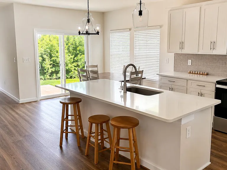 Open kitchen with a large island, bar seating, stainless appliances, and easy access to the patio for indoor-outdoor dining.