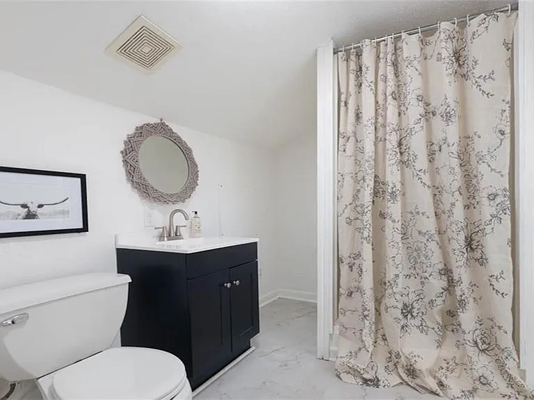 Well-appointed bathroom with a single-sink vanity, framed mirror, and a shower/tub with curtain for everyday convenience.