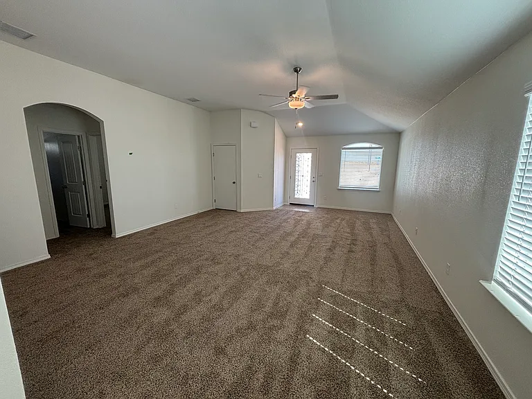 Spacious open-concept living room with abundant natural light and ceiling fan.