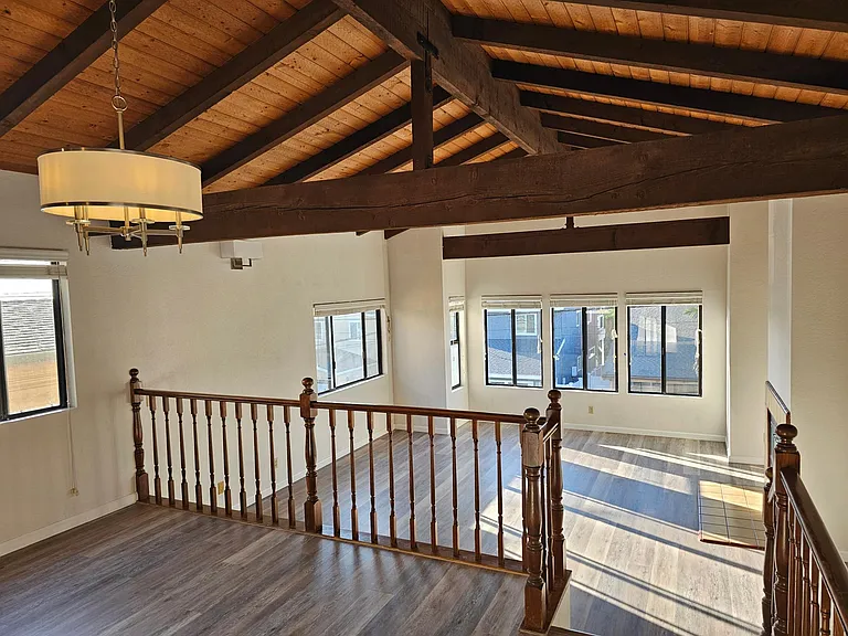 2nd story living room with vaulted beam ceilings and ocean view with elevated dining area.