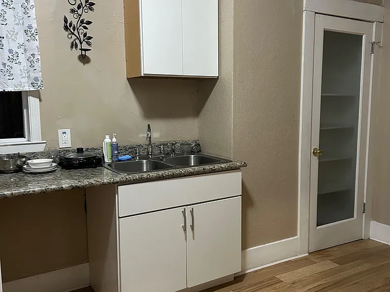 Compact kitchen workspace with granite-look counters, double-basin sink, and upper/lower cabinet storage.
