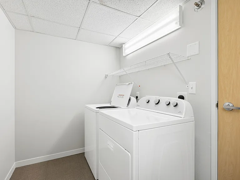 Sleek and modern laundry room featuring a washer and dryer set with ample overhead shelving. Sleek and modern laundry room featuring a washer and dryer set with ample overhead shelving.