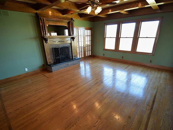 This magnificent living room exudes elegance, with an ornate fireplace and coffered ceilings. Two sets of french doors lead to the sun room & wrap around porch.