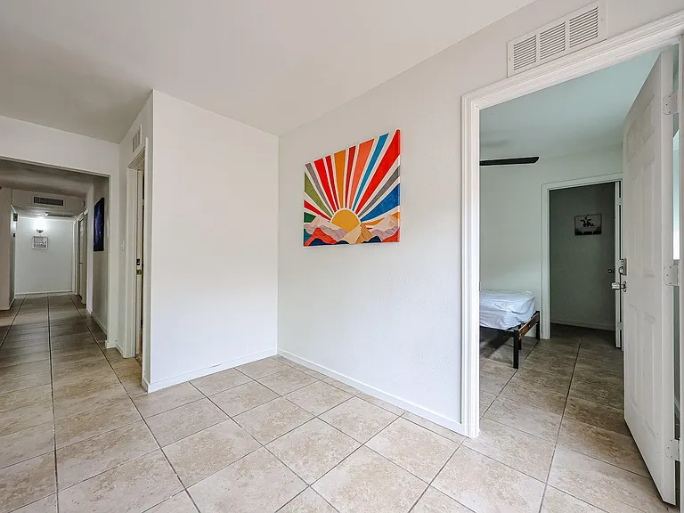 Wide tiled hallway with clean white walls and easy access to multiple rooms, creating a practical shared living layout.