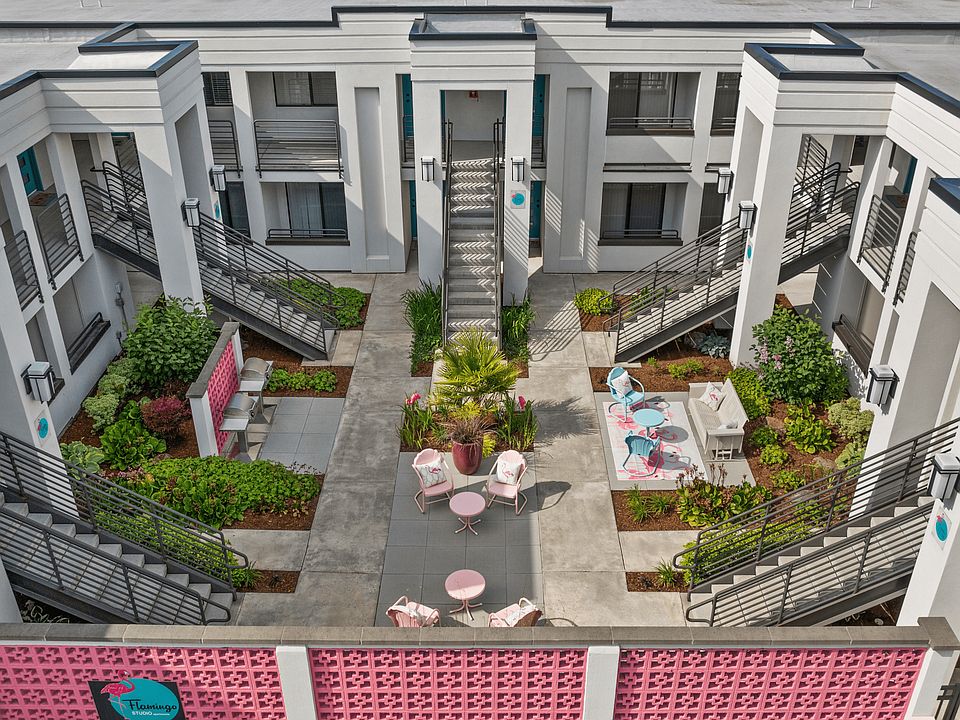 Charming apartment courtyard featuring stylish outdoor seating, lush greenery, and modern architecture, perfect for relaxation and community gatherings.