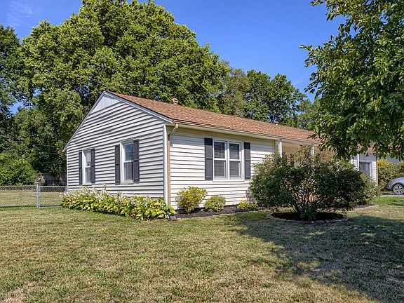 The front yard has several crabapple trees, rose bushes, and flowers.