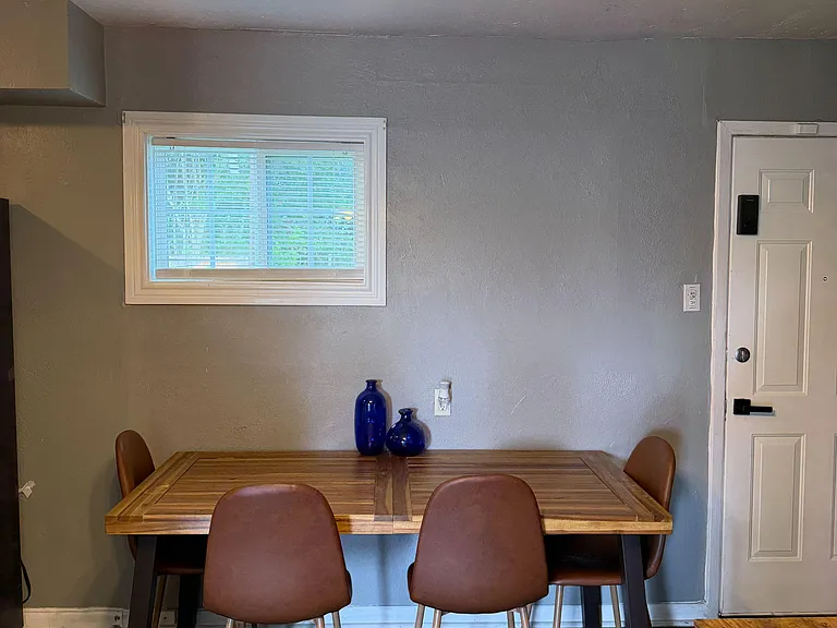 Dedicated dining area with a four-seat table, overhead fixture, and a window for natural lightideal for daily meals.