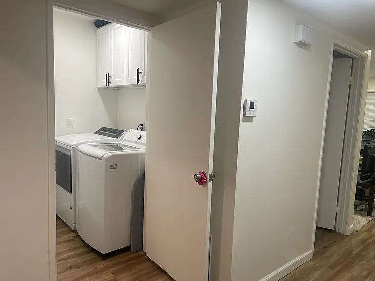 Laundry room (washer/dryer); open door on right is your full private bathroom, living room is further right (off-screen).