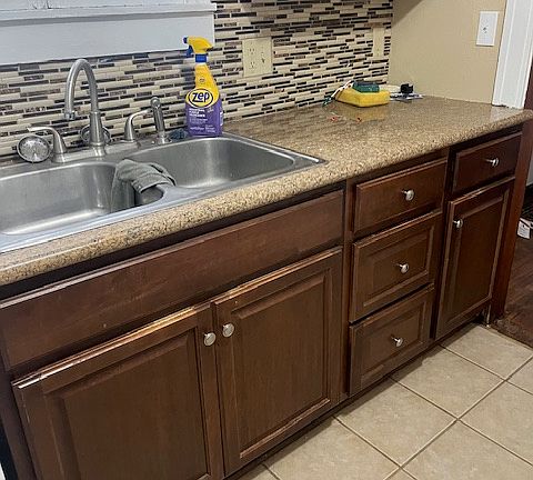 Double kitchen sink, granite countertops and tiled backsplash and flooring.