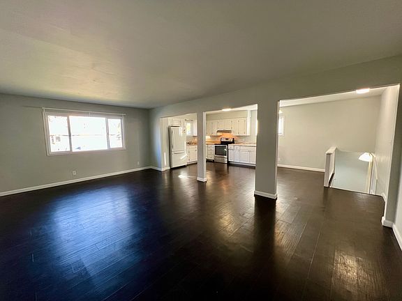 View of the kitchen & entryway steps from the far side of the living room. Hall to the right of the steps holds a large closet and access to the bedrooms & bathroom.