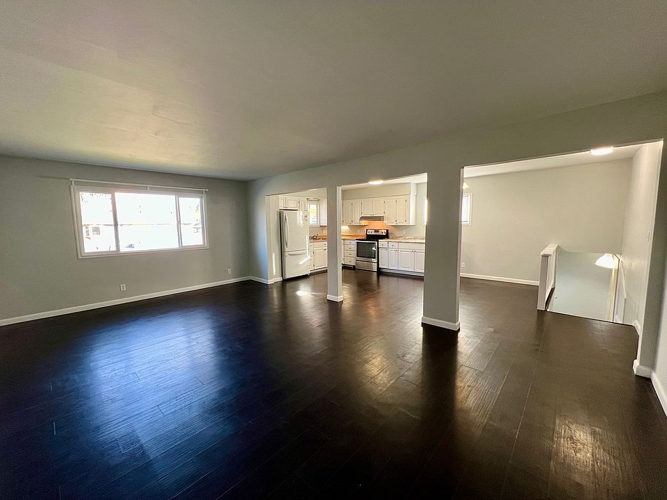View of the kitchen & entryway steps from the far side of the living room. Hall to the right of the steps holds a large closet and access to the bedrooms & bathroom.