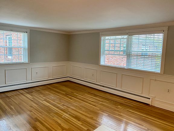 Living room with three windows and hardwood flooring.