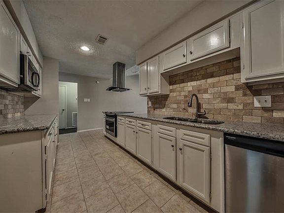 Galley kitchen with S/S appliances & granite countertops. To