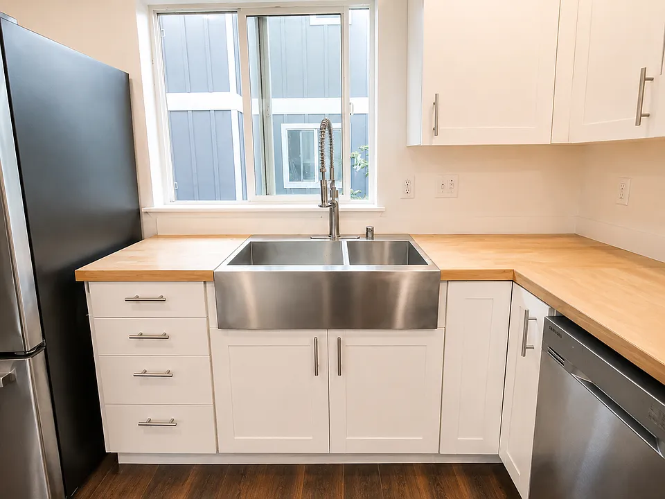 Large stainless-steel farmhouse-style sink with modern spring faucet and ample counter space.