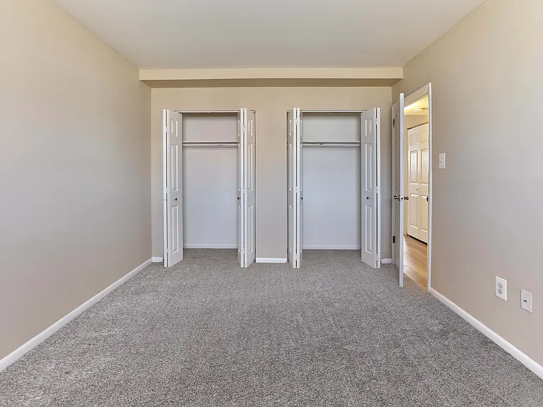 Comfortable, carpeted bedroom with ample closet space at Village Square.