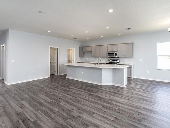 Open living area with vinyl plank flooring - New home for sale in Lake Alfred, FL. Photo showcases a