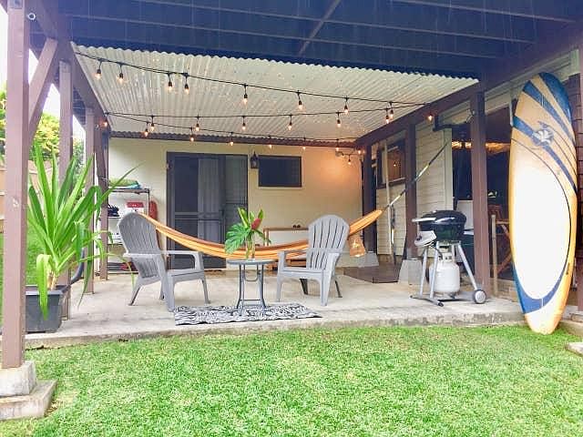 A large lanai looks onto a large yard filled with tropical landscaping.