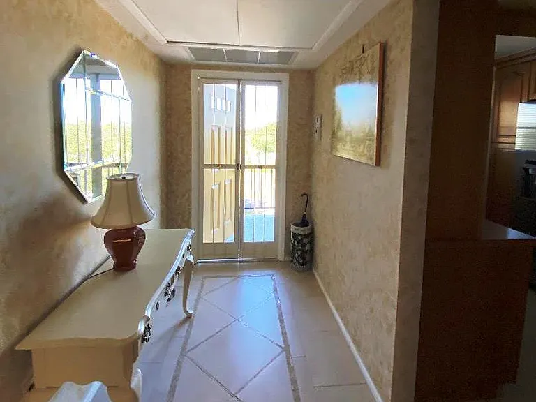 View through entrance hal toward exterior walkway. Doorway to kitchen is shown on the right.