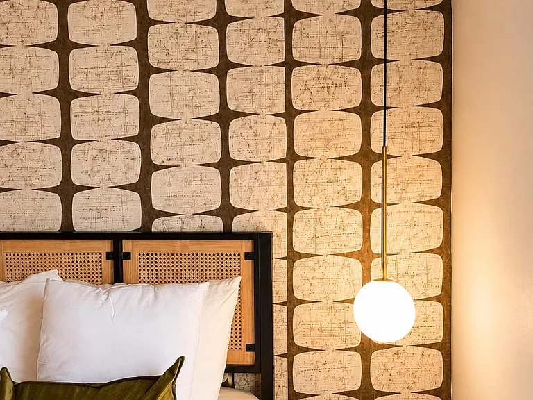 Sleeping area with a comfortable bed, statement accent wall, and pendant lighting for convenient bedtime reading.