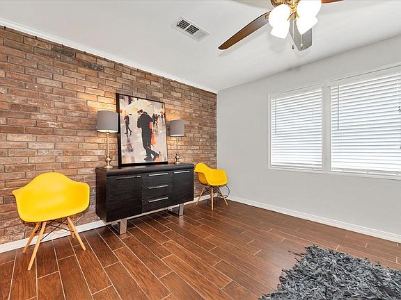 View of living room with cool brick accent wall & ceiling fan.