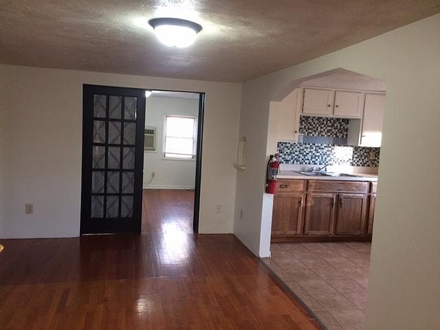Looking from the living room into one of the bedrooms and kitchen.