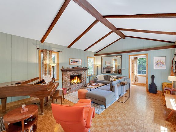 Cozy living room with baby grand piano and wood burning masonry fireplace, cathedral ceilings