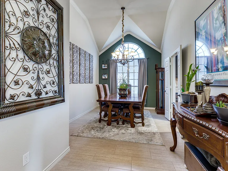 Large formal dining room with light hardwood / wood-style flooring, ornatmental molding, vaulted ceiling and an inviting chandelier.