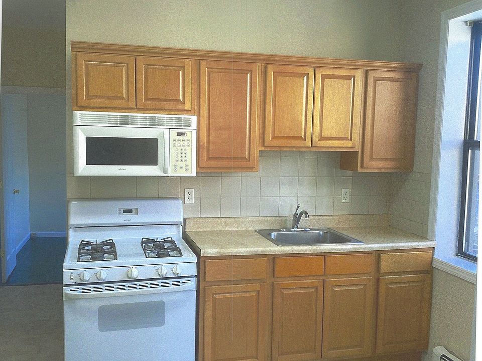 Sunny kitchen with modern cabinets and gas range and microwave.