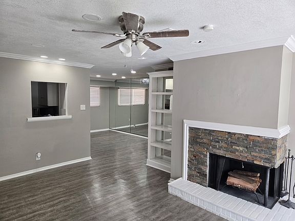 Living area with fireplace, ceiling fan and built-ins.