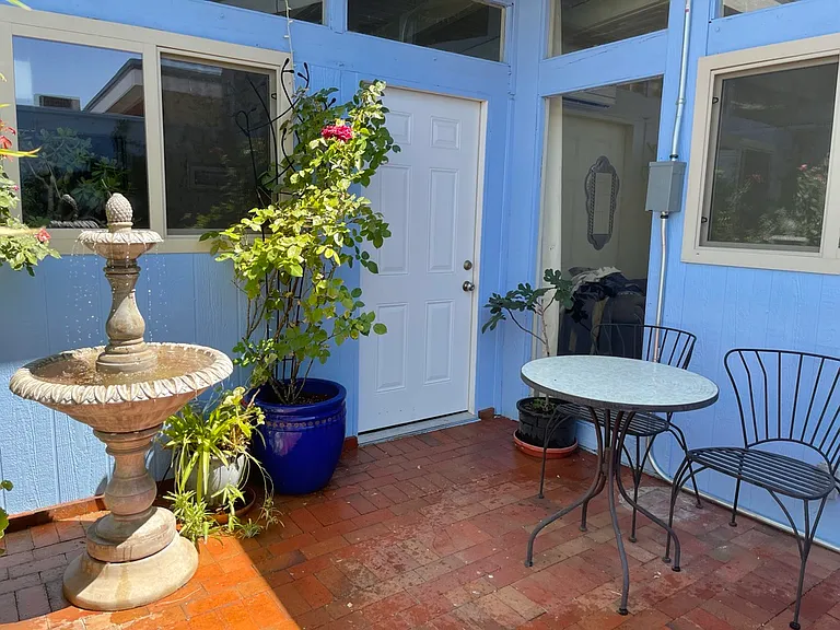 Private courtyard with potted plants and a functioning fountain.