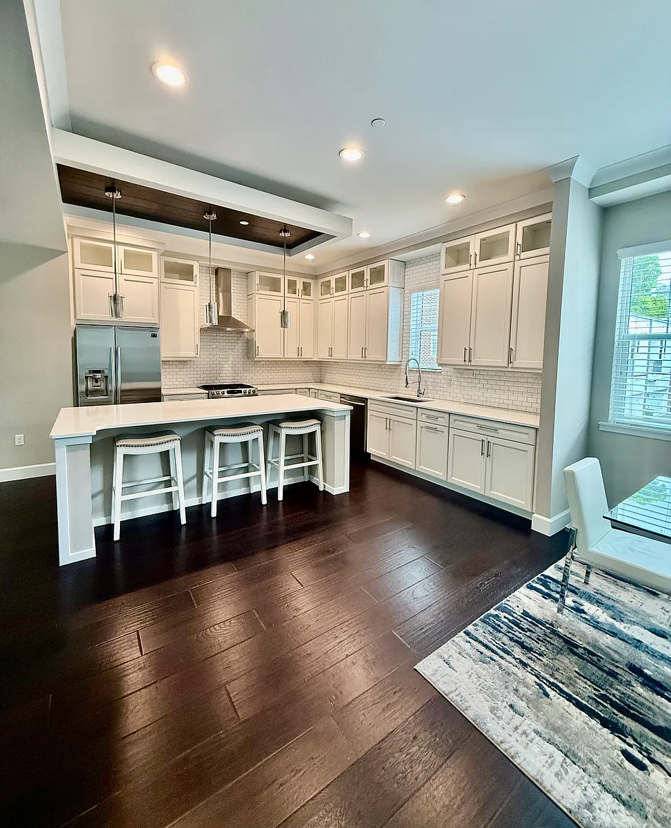Gourmet kitchen with custom inlay ceilings, granite countertops, glass front cabinetry, stainless steel appliances, a gas range, and an oversized center island with an open dining area and flowing seamlessly into a spacious family room. - 149 S Park Ave