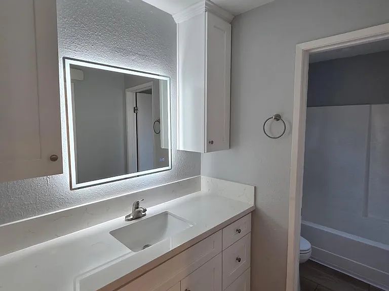Bathroom vanity with lighted mirror.