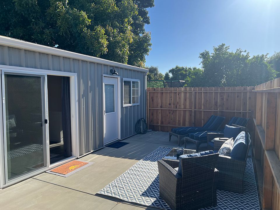 Large outside fenced in patio with new patio conversation set, two chaise loungers, and lots of sunshine.