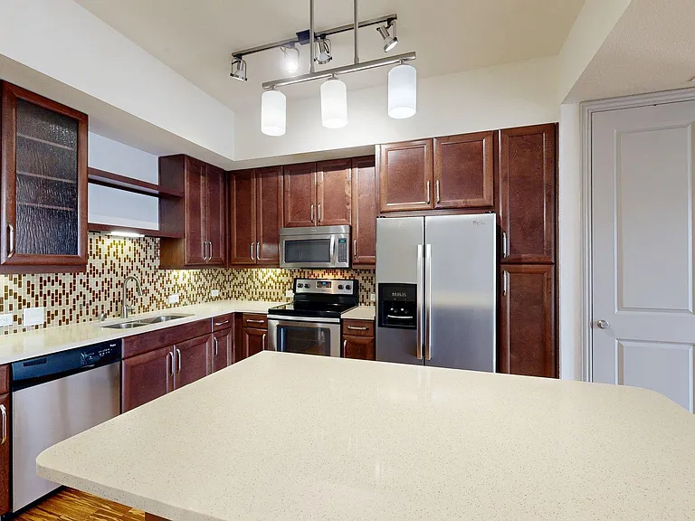 Apartment kitchen with stainless steel appliances and light counters.