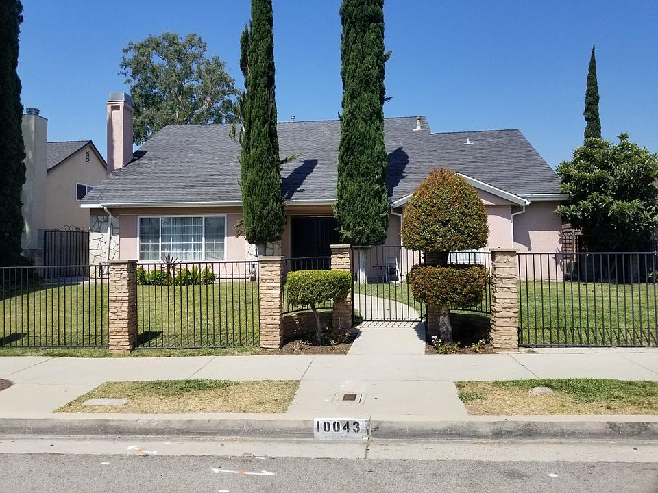 Street view with gated front yard. Gated driveway and garage access from the back alley