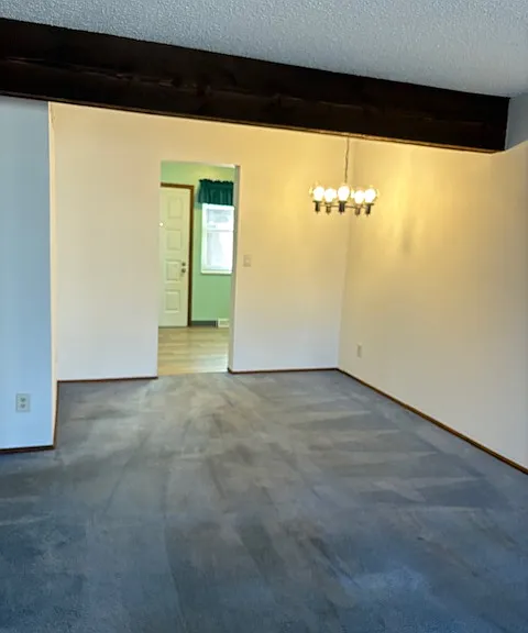 Dining area under the chandelier looking into kitchen