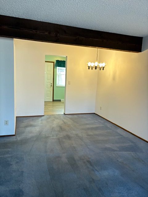 Dining area under the chandelier looking into kitchen