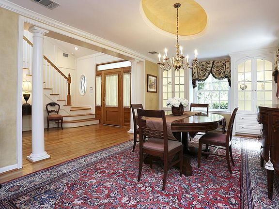 Dining room has raised oval ceiling, lighted glass cabinets and several windows with views to side a