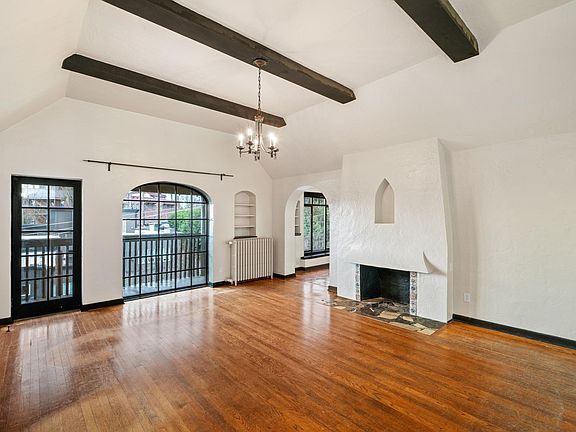Spacious living room, 10-foot vaulted and beamed ceiling. Faux decourative fireplace. Hardwood floors. Balcony access with southern and west views of South Lake Union, Olympic Mountain and sunsets.