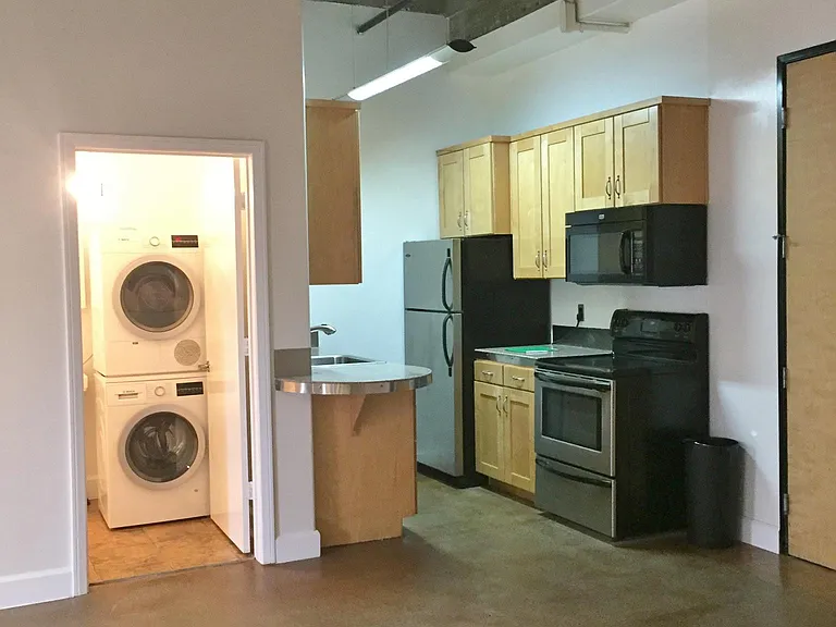 This is a view towards the kitchen and the restroom which has the compact washer and dryer.
