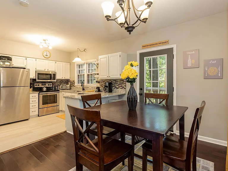 Eat-in kitchen with stainless appliances, ample cabinetry, and a dining nook beside a glass door for easy outdoor access.