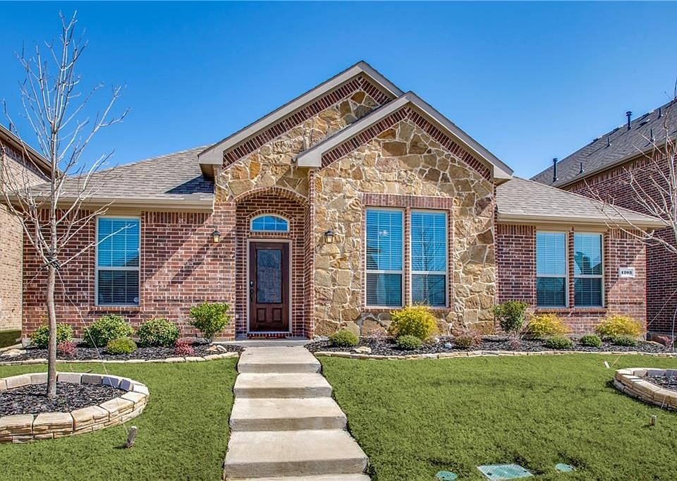 Welcome Home to 1203 Stampede. Landscaping touches including stonework surrounding flowerbeds and trees.