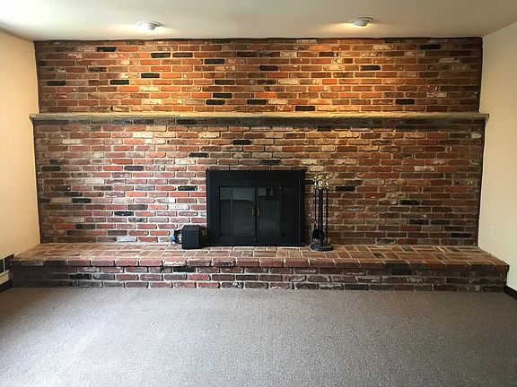 Wood-burning fireplace and exposed brick wall in living room
