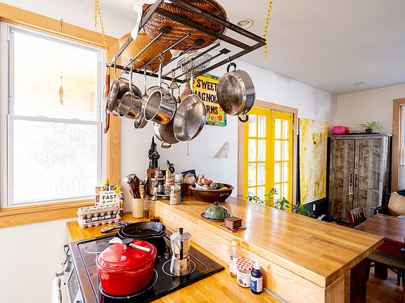 Kitchen stove/oven with tall bar and hanging pots and pans.