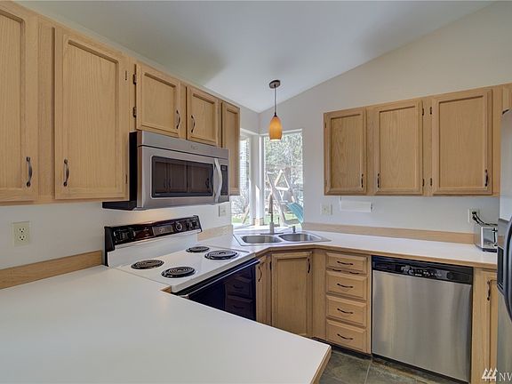 The kitchen features a peninsula with bar stool seating and a corner window overlooking the back yard.