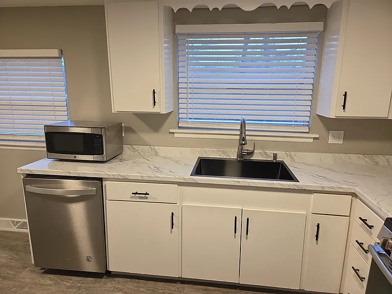 Bright kitchen with updated countertops, white cabinetry, stainless refrigerator and range, and dishwasher.
