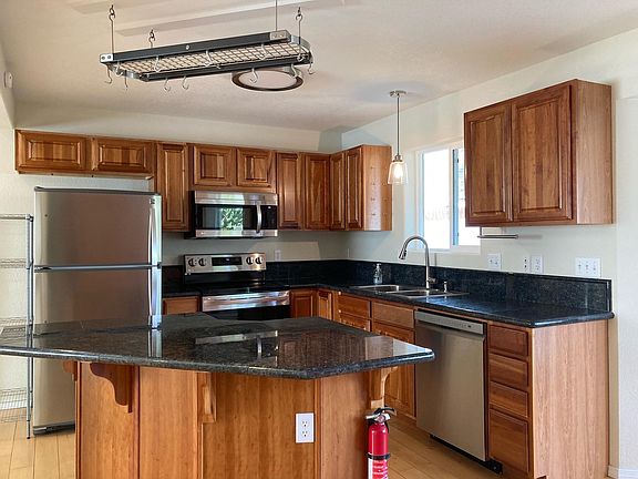 The kitchen has several new appliances, hanging pan rack, and a generously sized breakfast bar that fits several stools.
