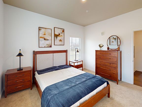 The Jane bedroom is spacious with natural light from windows on two walls.